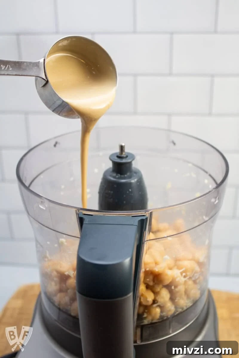 Classic Hummus from Canned Chickpeas – Quick Authentic Recipe 7 Adding tahini to hummus ingredients in a food processor.