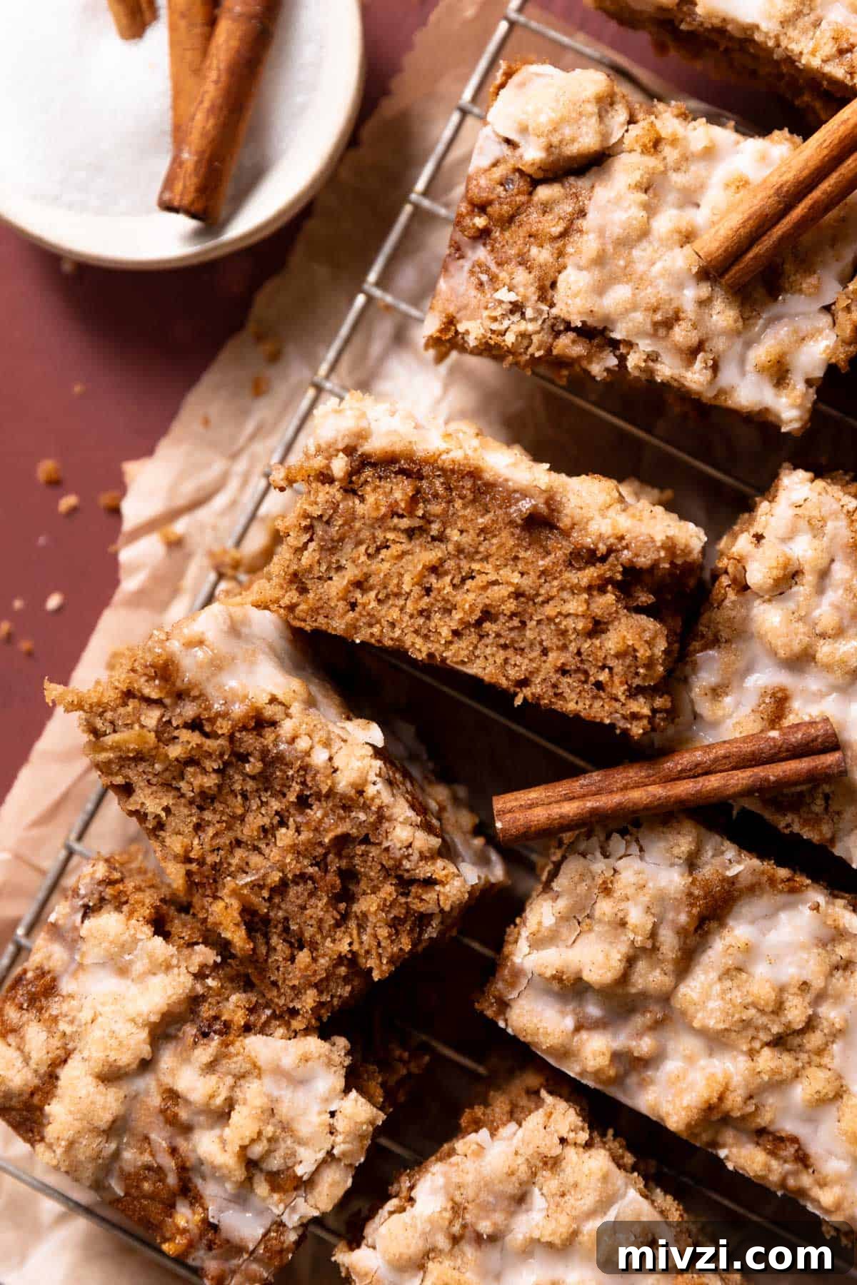 Slices of cinnamon apple cake on a wire rack drizzled with vanilla glaze.