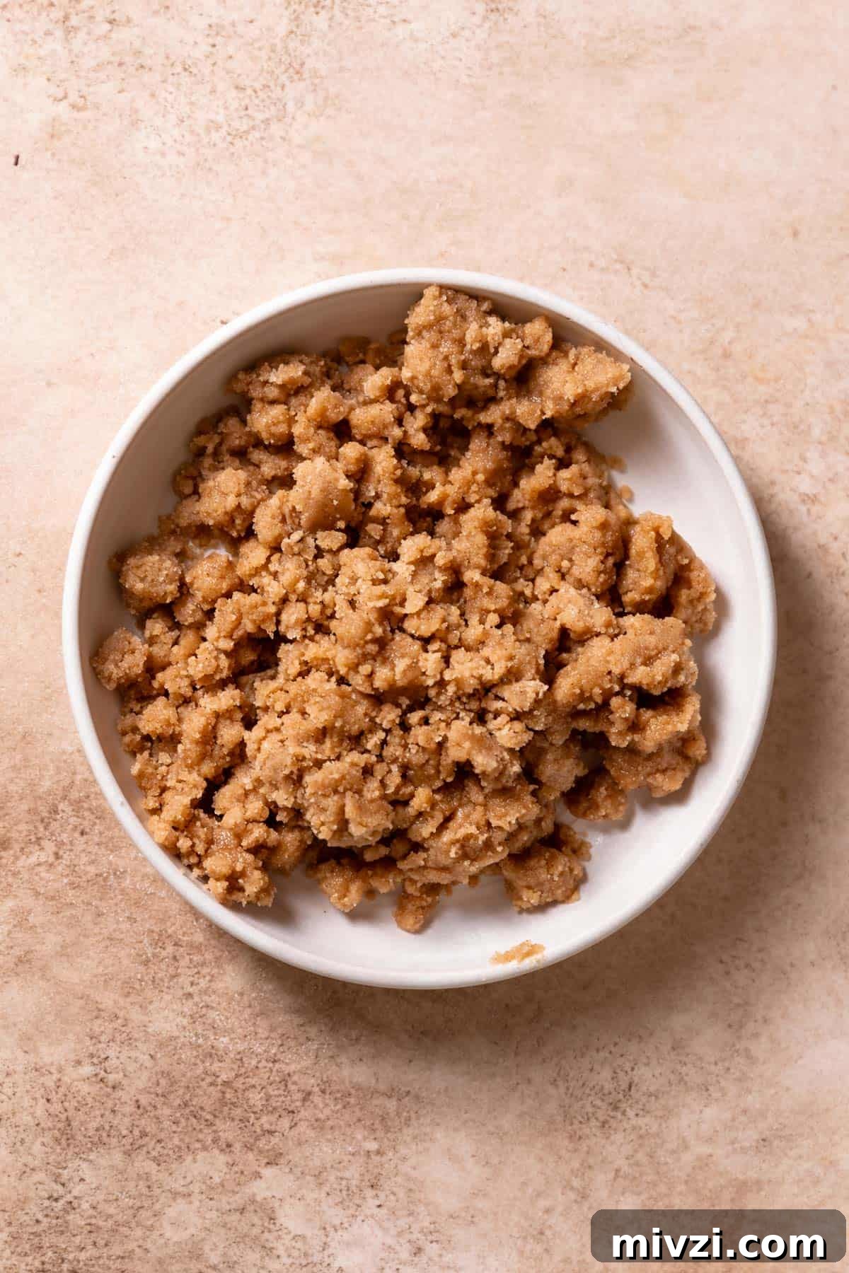 A white bowl with cinnamon crumb topping.