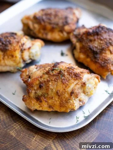 Seasoned baked chicken thigh on a serving dish.