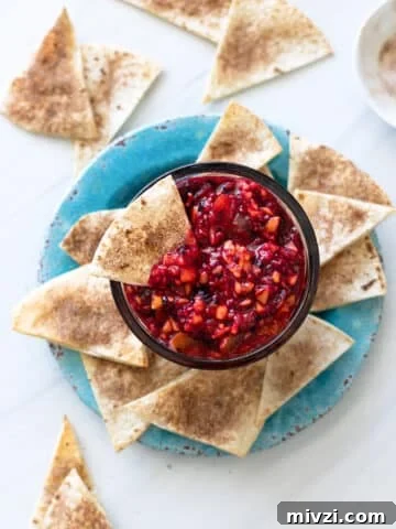 Bowl filled with fruit salsa and cinnamon chips being served alongside.