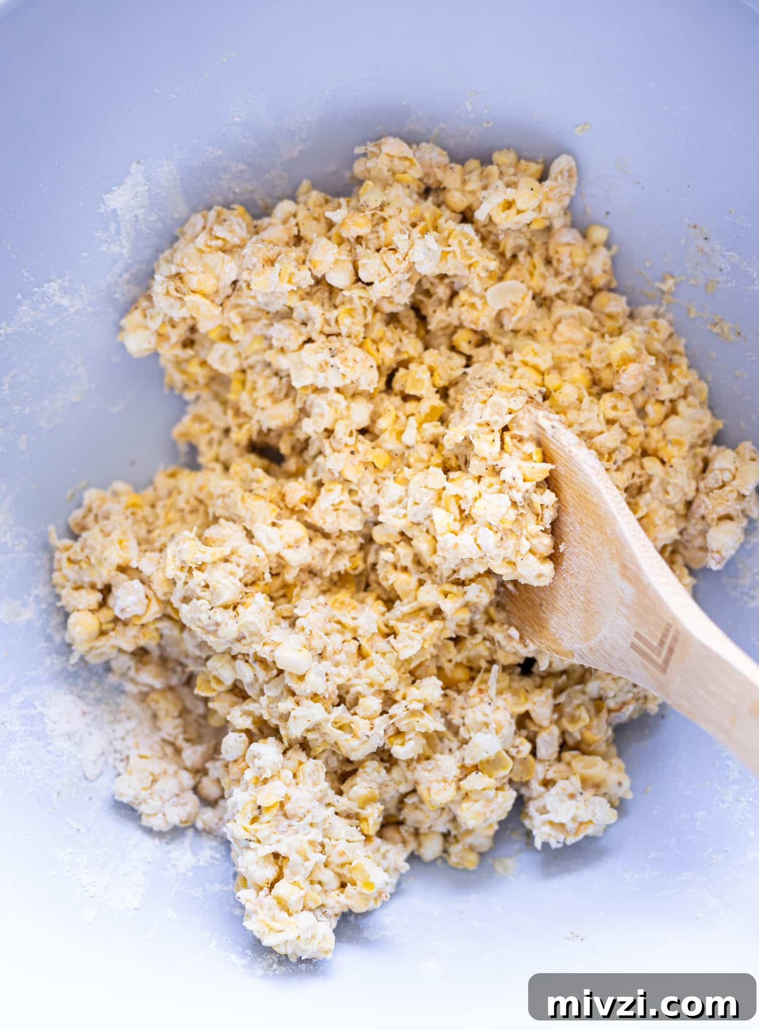 Corn and flour being stirred in a bowl.