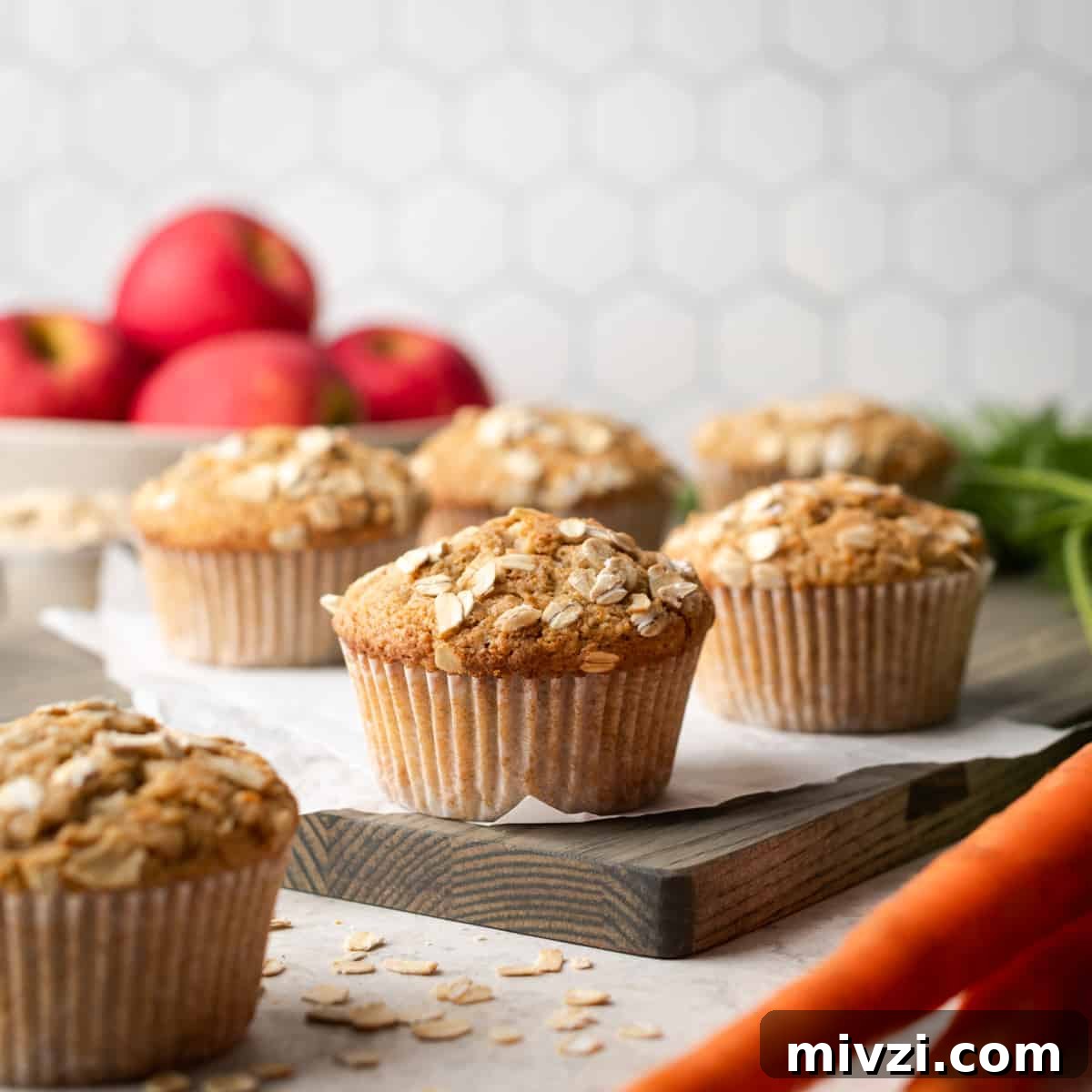 Applesauce carrot muffins sitting on a wooden cutting board.