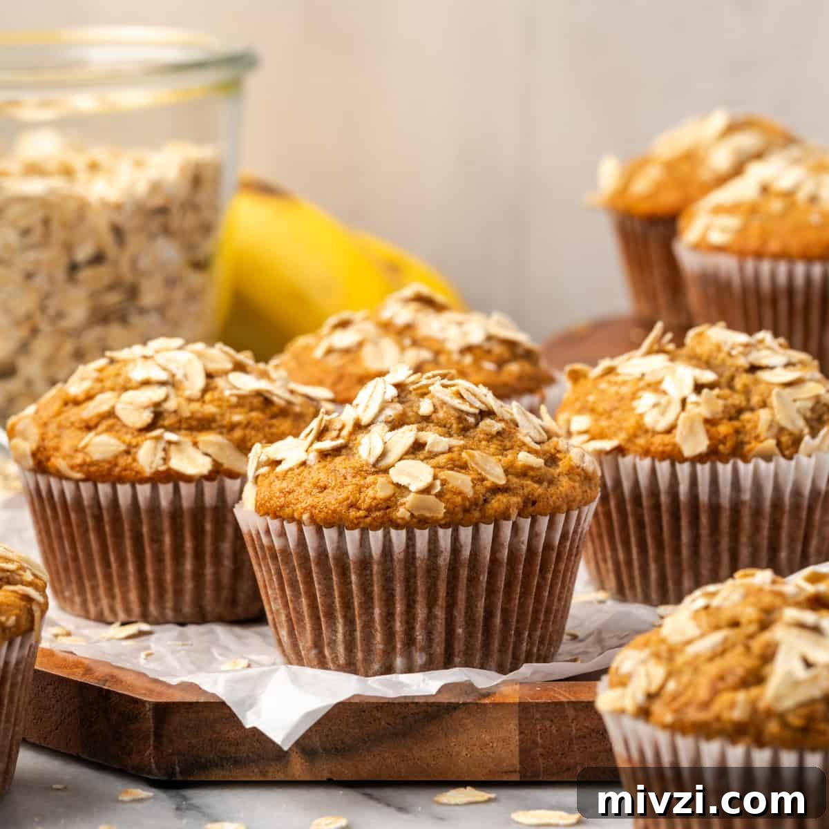 Several banana oat flour muffins sitting on a wooden tray.