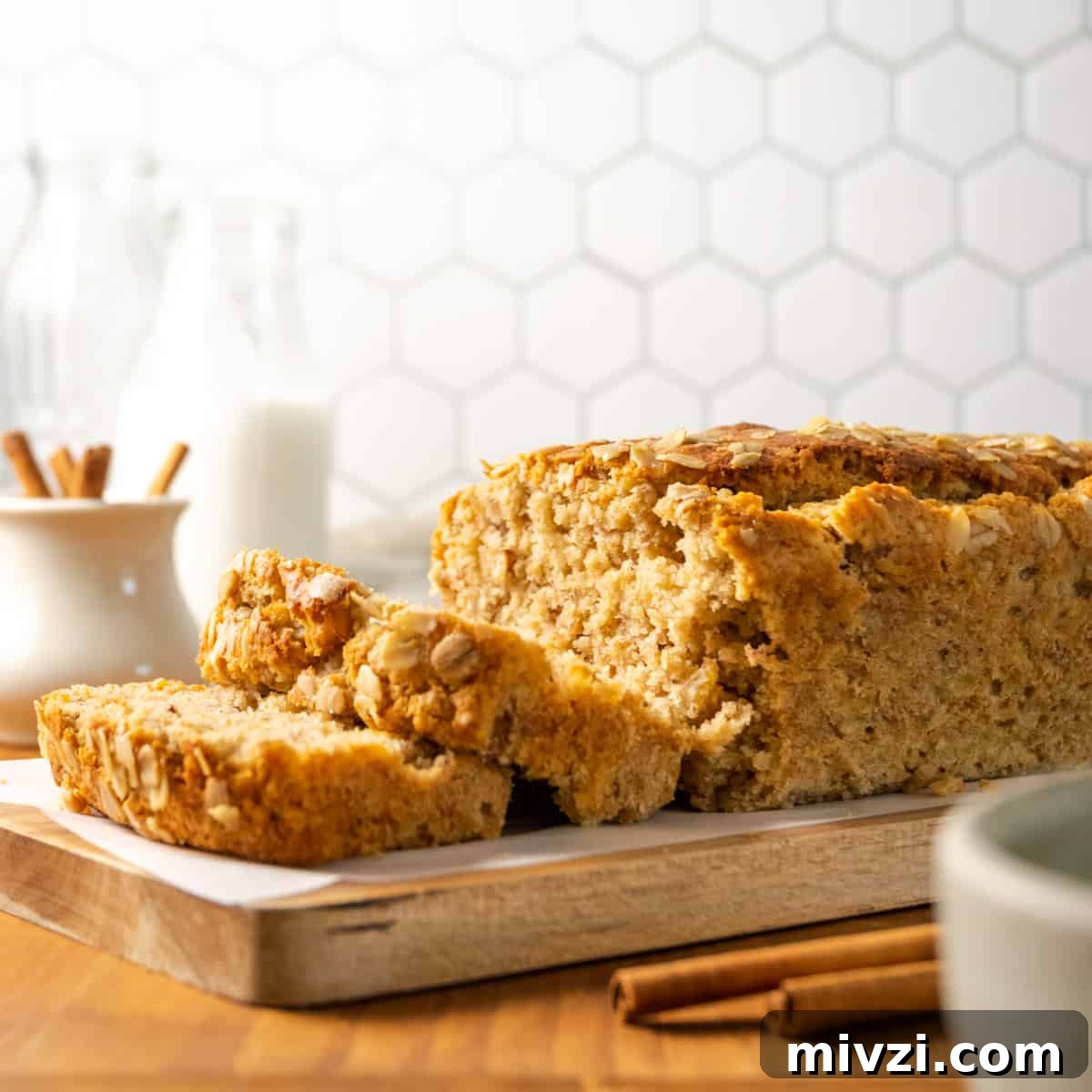 A loaf of maple banana bread sliced and sitting on a wooden cutting board.