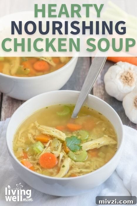bowl of hearty nourishing chicken soup in a white bowl on white napkin with garlic and carrots