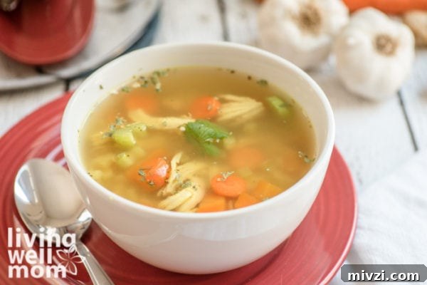 White bowl filled with a soup that has chicken, broth, and veggies