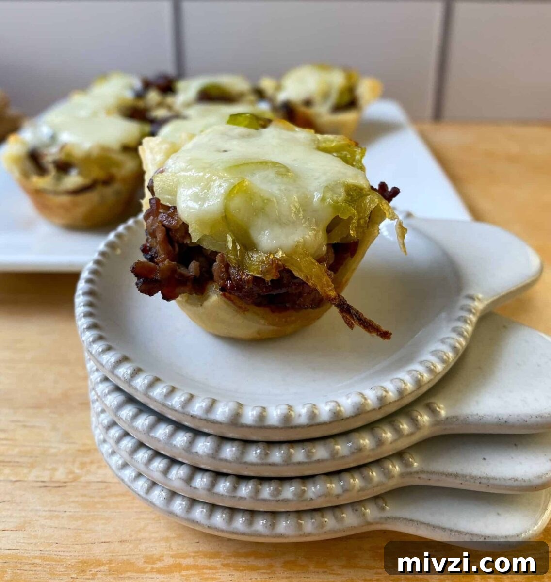 Mini Philly Cheesesteak Sliders: Bite-Sized Steak & Cheese Delight 11 mini cheesesteak bite on a stack of tasting plates.