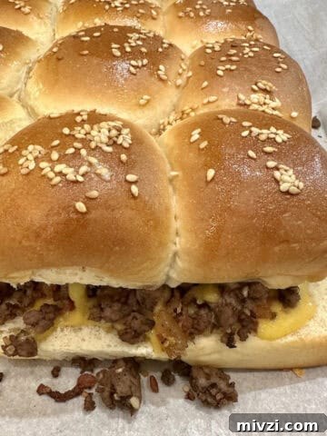 A pan of baked cheeseburger sliders on a baking sheet.