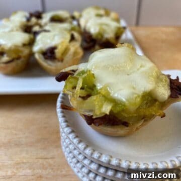 Philly Cheesesteak bite on a small stack of dishes with the serving plate in the background.