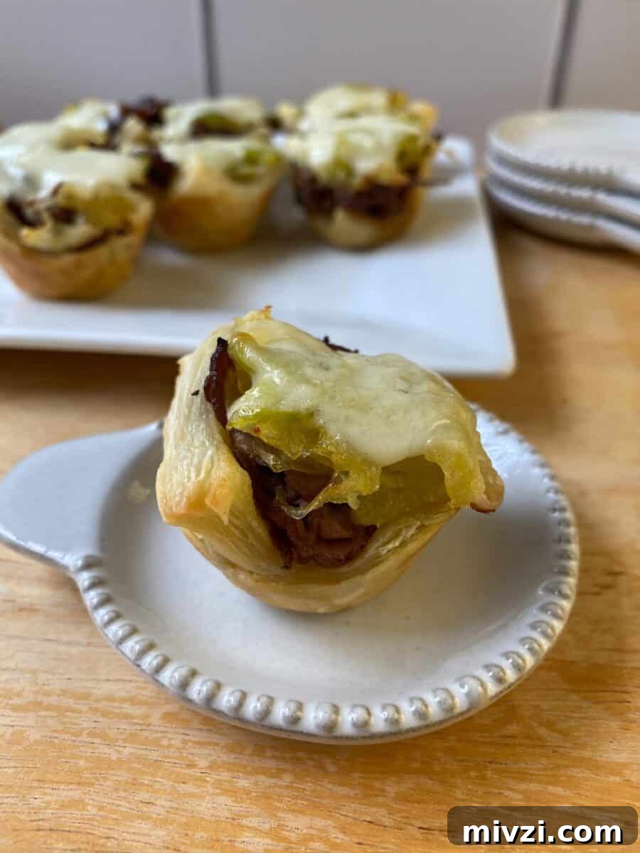 Mini Philly Cheesesteak Sliders: Bite-Sized Steak & Cheese Delight 9 A Philly Cheesesteak Bite on a small plate, with a larger plate in the background and additional bites on display.