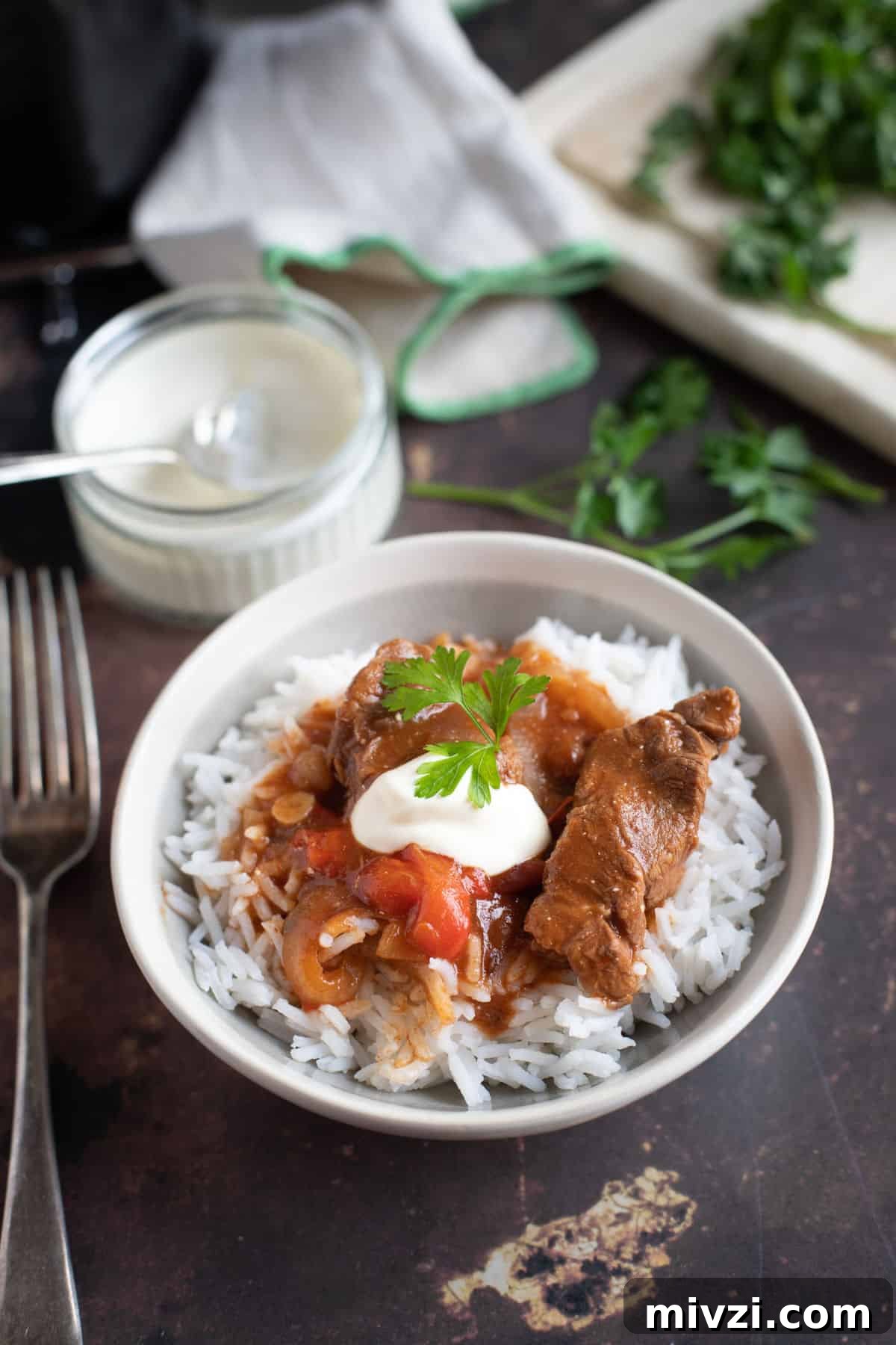 Hearty Slow Cooker Beef Goulash Recipe for Tender, Savory Meals 4 Slow cooker beef goulash served on a bed of rice with soured cream and parsley.