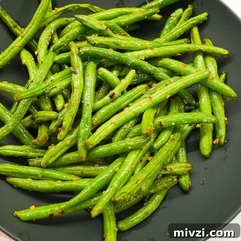 Crispy Air Fryer Green Beans with Garlic and Parmesan 2 Air fryer green beans in a bowl with visible garlic, red pepper flakes, and lightly blistered edges.