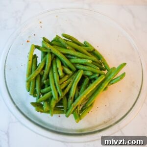 Crispy Air Fryer Green Beans with Garlic and Parmesan 5 Green beans in a glass bowl with seasonings.