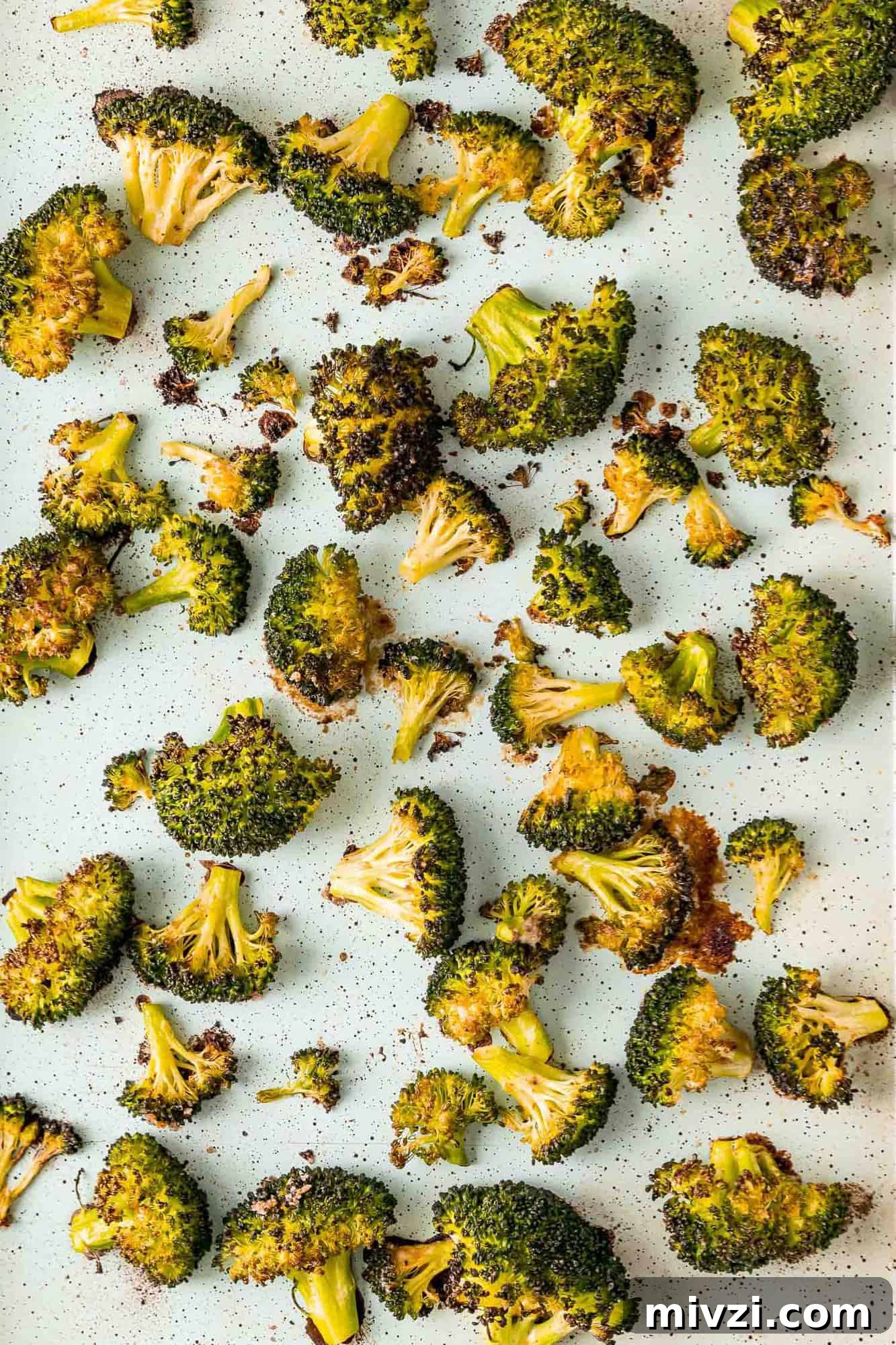 Roasted broccoli on a parchment paper lined sheet pan.