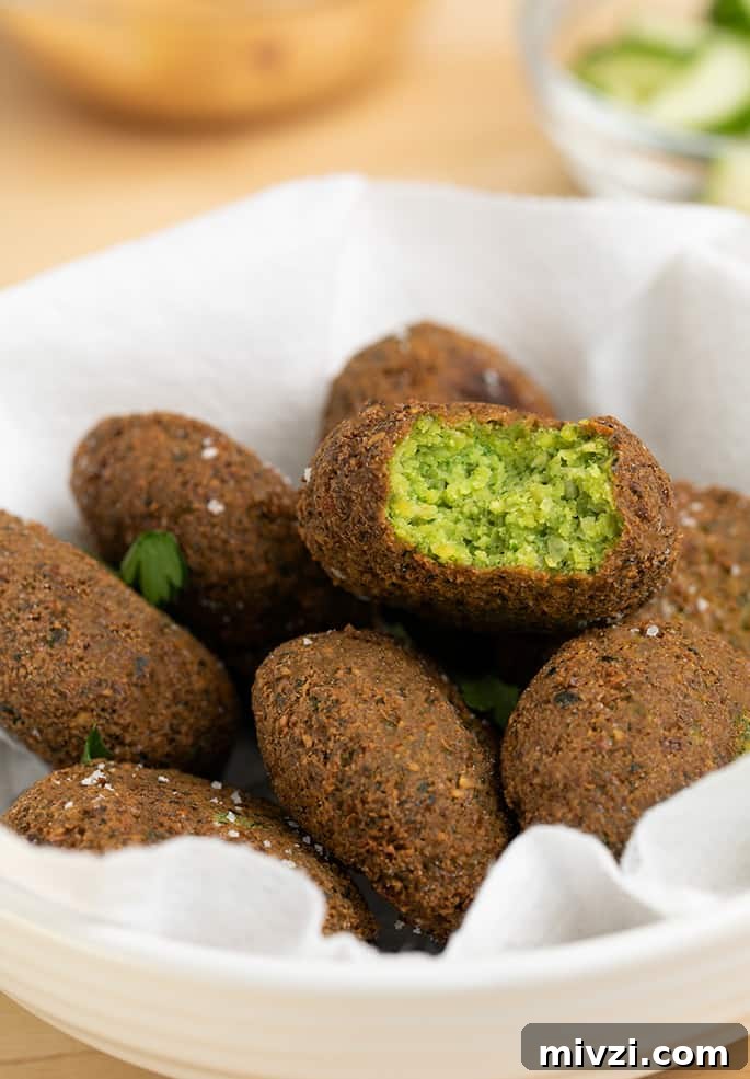 Pile of falafel in white bowl one with bite taken