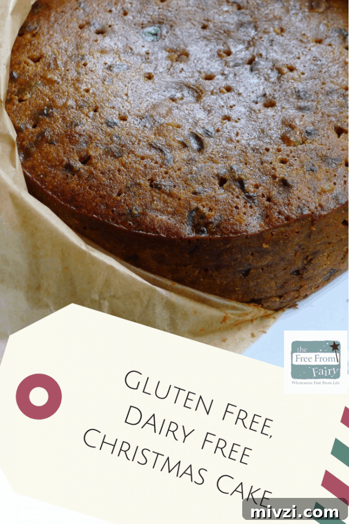 Dairy-Free Gluten-Free Christmas Cake Recipe 12 A pinterest graphic showing the undecorated fruit cake partially wrapped in parchment with the recipe name on a gift tag shaped label underneath.