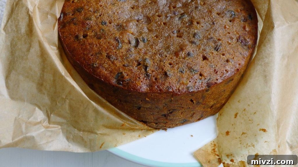 Dairy-Free Gluten-Free Christmas Cake Recipe 3 A whole undecorated Gluten Free Christmas Cake shown partially wrapped in parchment paper.