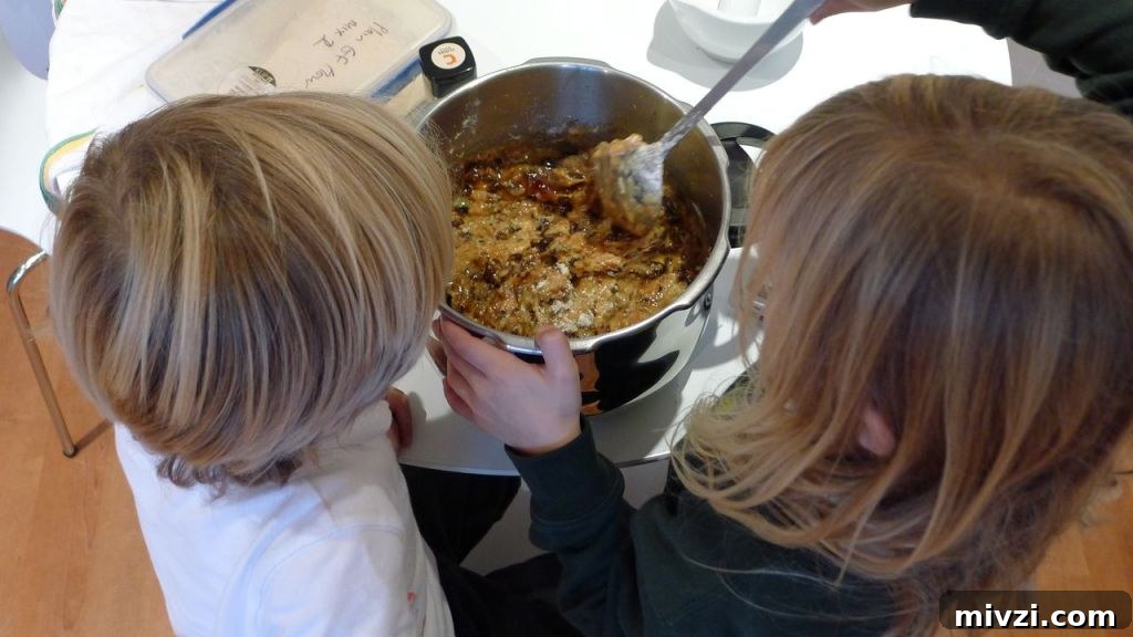 Dairy-Free Gluten-Free Christmas Cake Recipe 6 Overhead shot of two children mixing the cake batter together in a silver bowl.