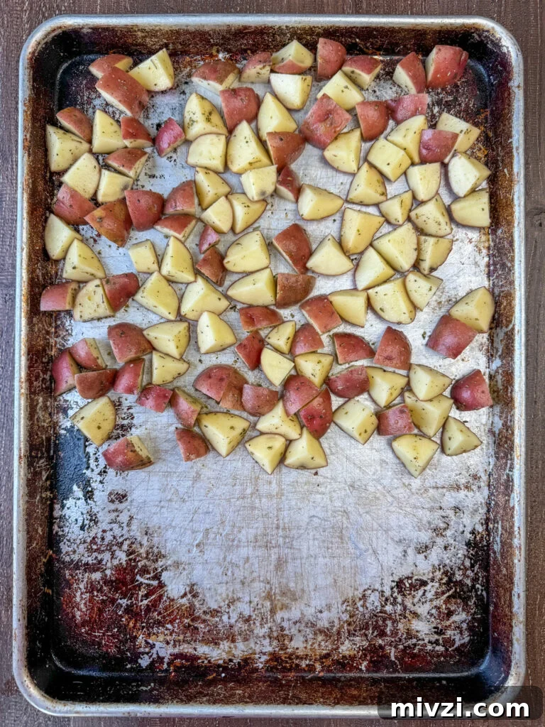 Seasoned potatoes on a baking sheet.