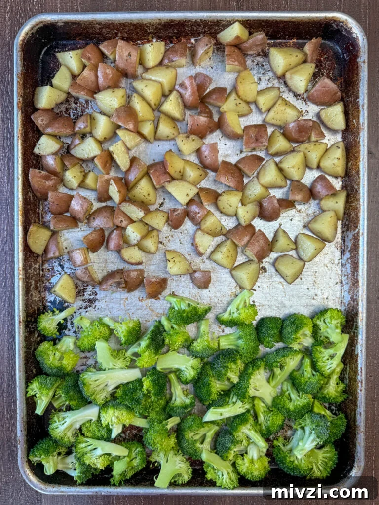 Seasoned potatoes and broccoli on a baking sheet.