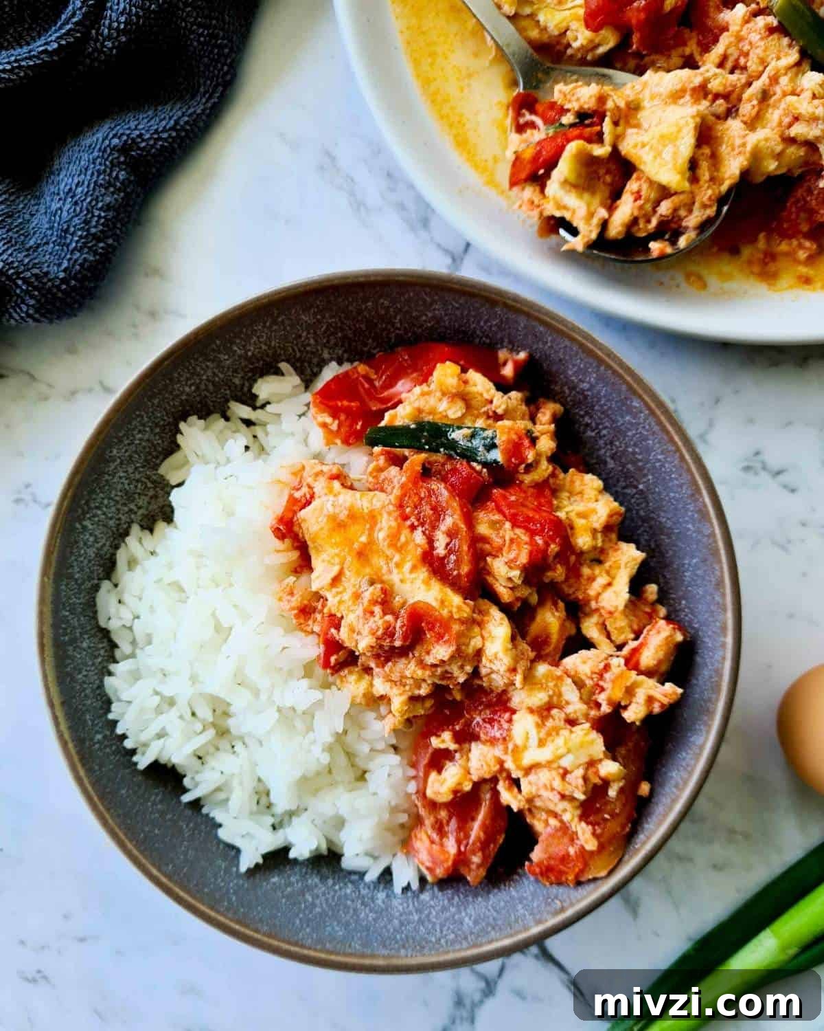 A bowl of rice topped with chinese tomato and egg stir fry