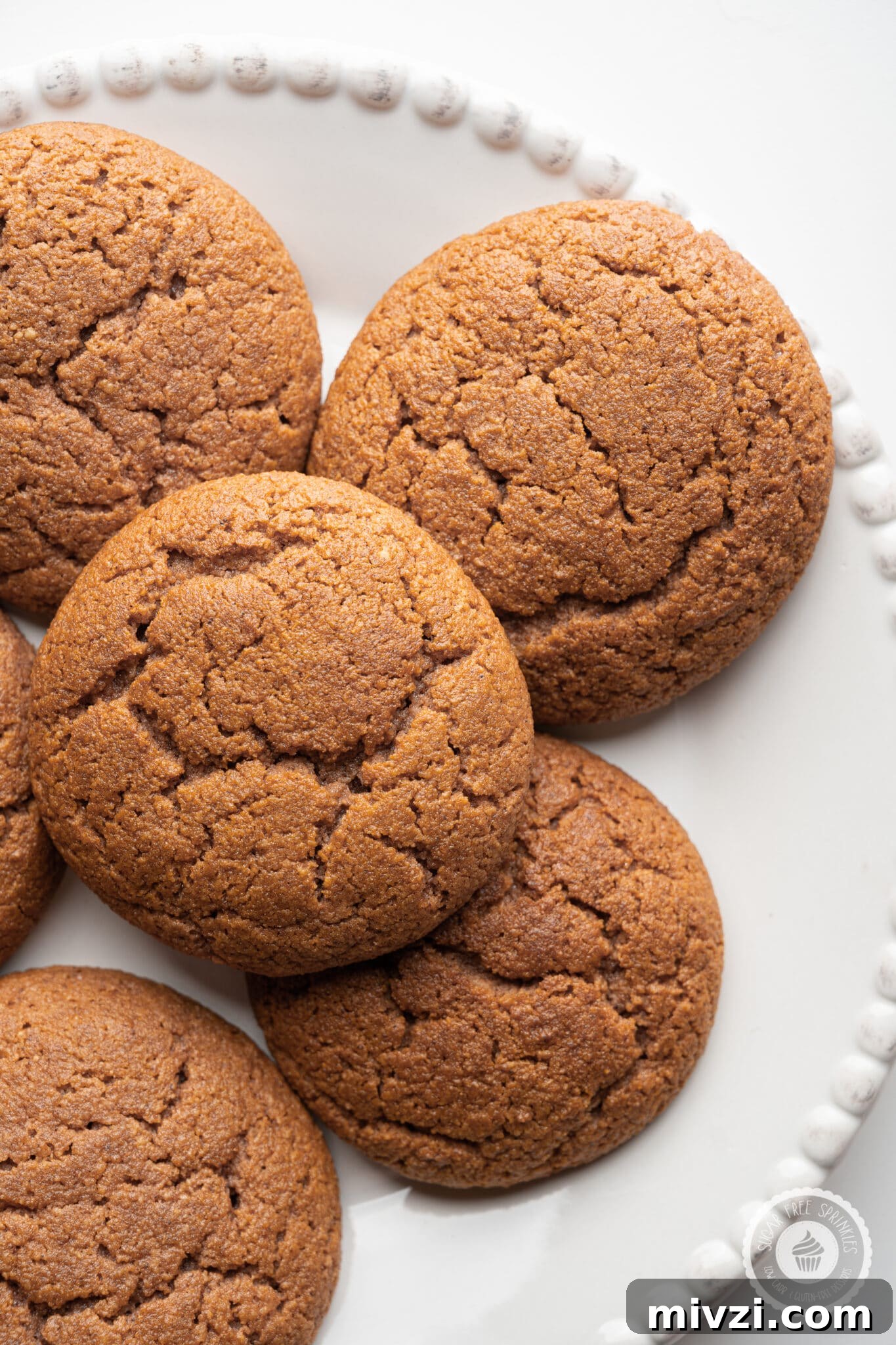 Soft Keto Gingerbread Cookies: Chewy Low-Carb Holiday Treat 2 A white plate with crackle style keto gingerbread cookies stacked on top.