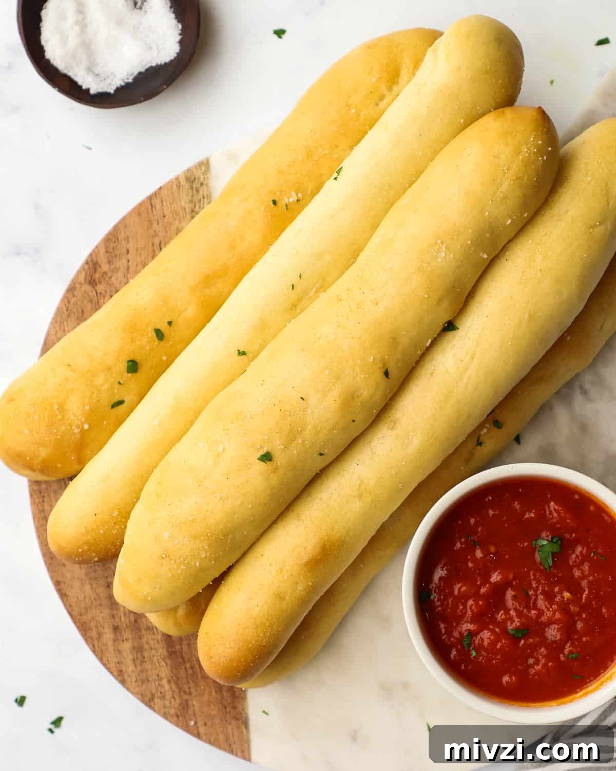 Crispy Homemade Breadsticks Recipe for Perfect Dinner Sides 12 overhead view of 6 breadsticks on a serving board with marinara sauce