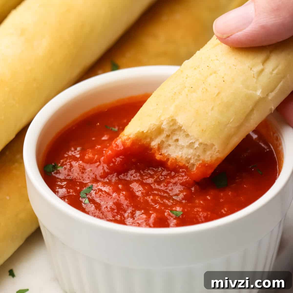 Crispy Homemade Breadsticks Recipe for Perfect Dinner Sides 13 a breadstick being dipped into marinara sauce