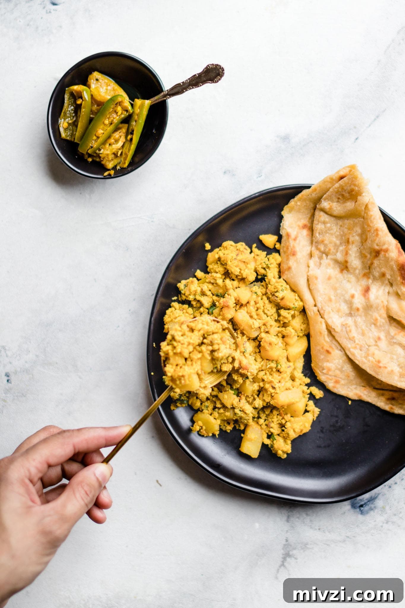 Spiced Potato and Egg Bhurji (Aloo Anday Ki Bhujia) 4 Holding a spoon with scrambled egg and potato curry over a plate
