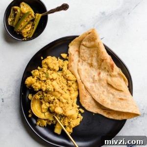 Spiced Potato and Egg Bhurji (Aloo Anday Ki Bhujia) 7 Scrambled Egg and Potatoes and paratha on a black plate with a gold spoon