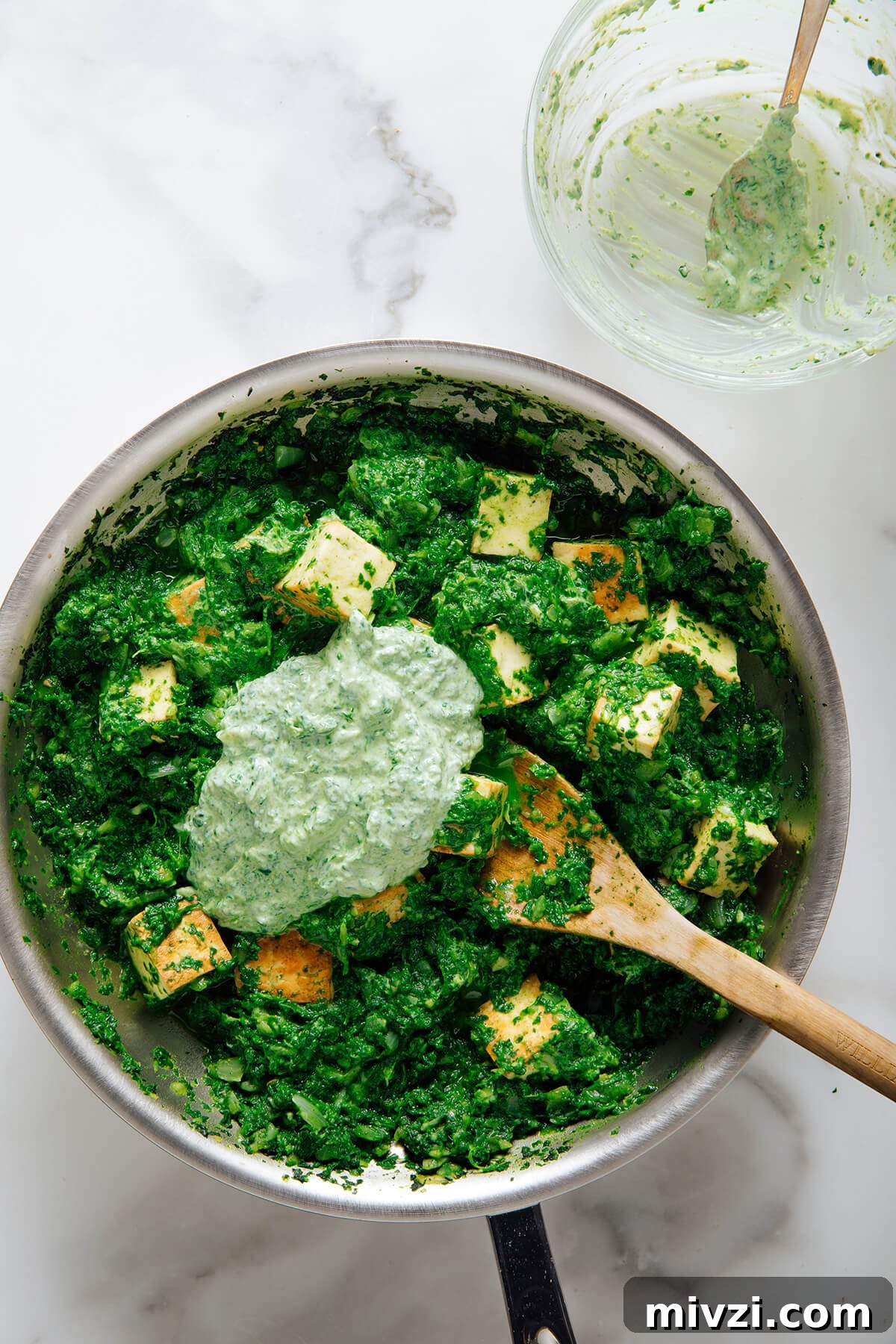 stirring tempered yogurt into palak paneer