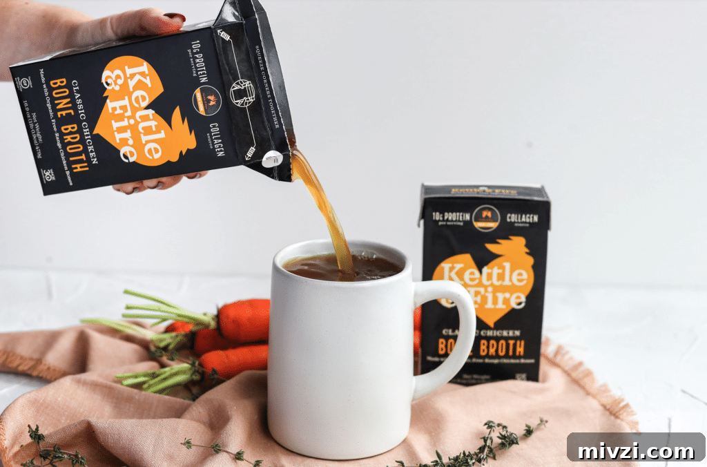 White mug with a black carton of bone broth being poured into it and more broth containers behind them.