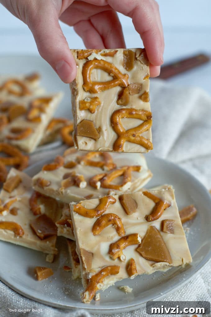 Cookie Butter White Chocolate Bark Recipe | Crunchy Cookie Butter Bark 3 a hand holding a piece of candy bark