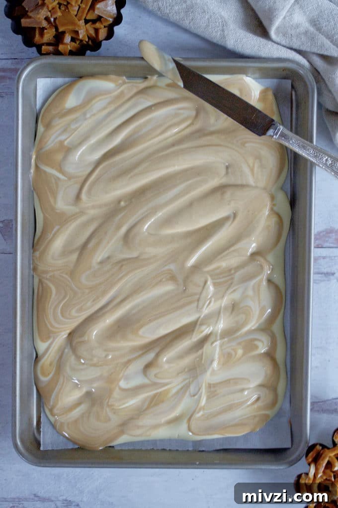 Cookie Butter White Chocolate Bark Recipe | Crunchy Cookie Butter Bark 9 melted white chocolate and cookie butter swirled together on a baking sheet