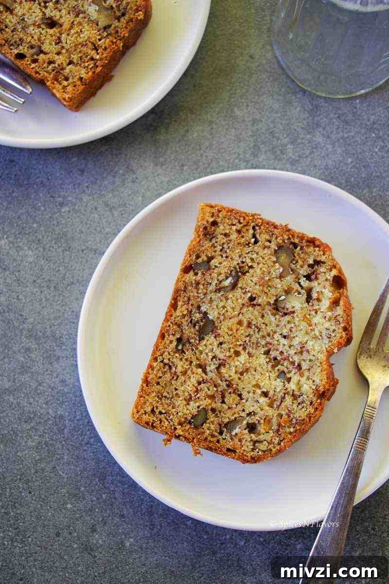 Moist Vegan Banana Bread Recipe with Simple Ingredients 11 close up overhead image of banana bread slice placed on a white plate with a fork on the side