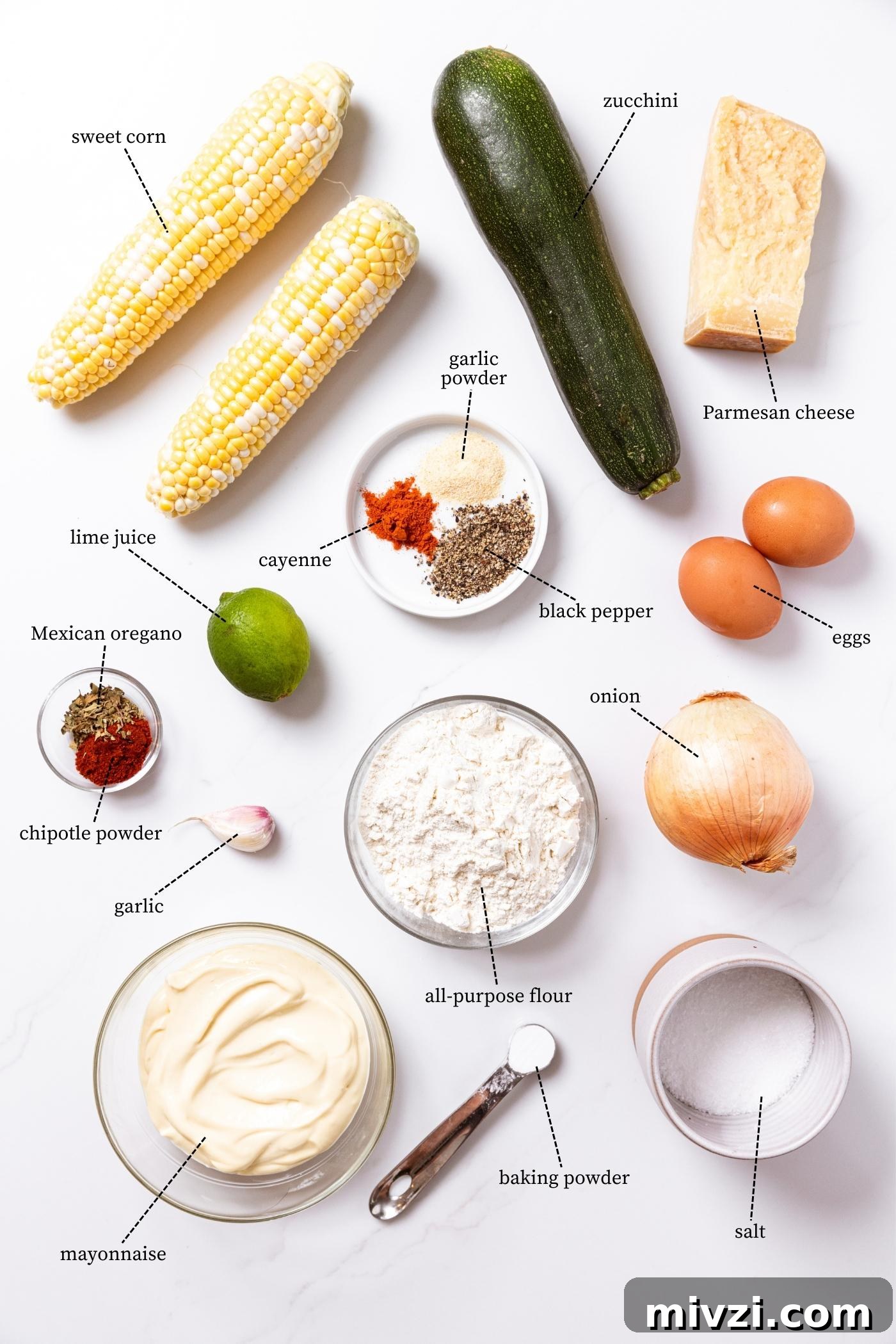 White countertop filled with ingredients needed to make zucchini and corn fritters including corn, zucchini, Parmesan cheese, spices, eggs, and more.