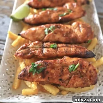 Grilled chicken tenders on a platter with fries.