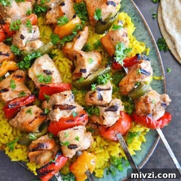 A top view of a platter with chicken kabob skewers on yellow rice.