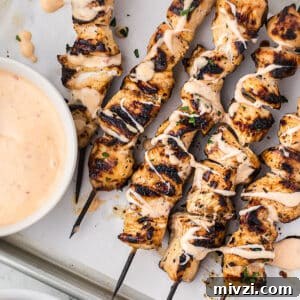 Spicy Bang Bang Chicken Skewers Recipe for Grilled Poultry 10 Sheet pan with grilled chicken skewers drizzled with bang bang sauce.