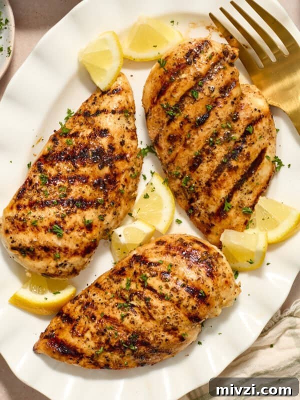 Mediterranean-Style Grilled Chicken with Lemon and Herbs 13 Grilled lemon pepper chicken on white serving platter with lemon wedges.