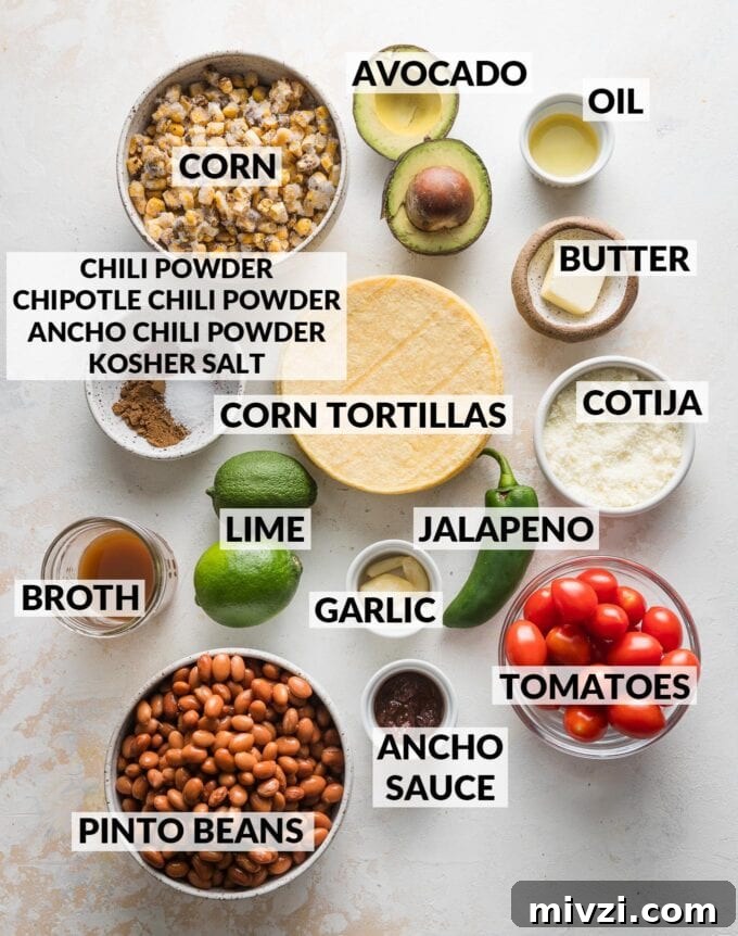 Pinto Bean Tostadas with Fresh Tomato and Corn Salsa 3 Labeled overhead photo of corn tortillas, corn, pinto beans, tomatoes, a whole avocado, oil, butter, Cotija, garlic, jalapeno, limes, ancho sauce, broth, and spices, all measured and ready to cook.
