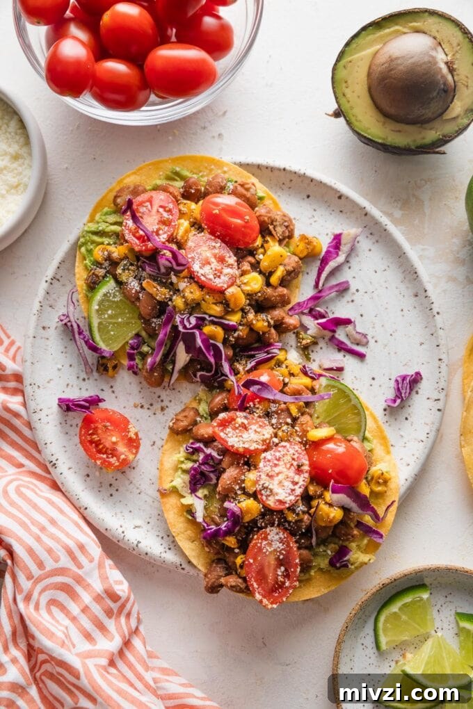 Pinto Bean Tostadas with Fresh Tomato and Corn Salsa 7 Countertop with a plate full of pinto bean tostadas, surrounded by extra salsa, tomatoes, avocado, and lime.