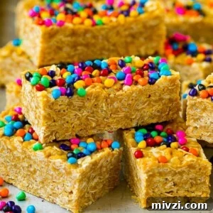 Cereal bars stacked on a sheet pan topped with colorful sprinkles.