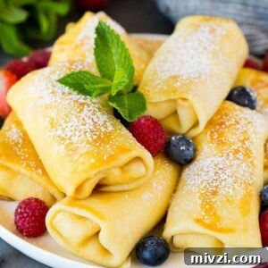Cheese blintzes garnished with powdered sugar and berries.