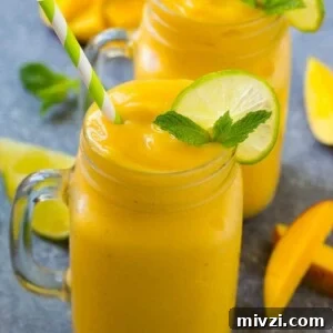 Mango smoothie in a mug topped with a slice of lime and mint sprig.