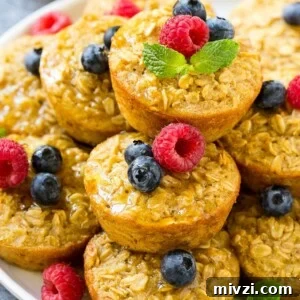 Baked oatmeal cups on a platter topped with maple syrup, berries and mint.