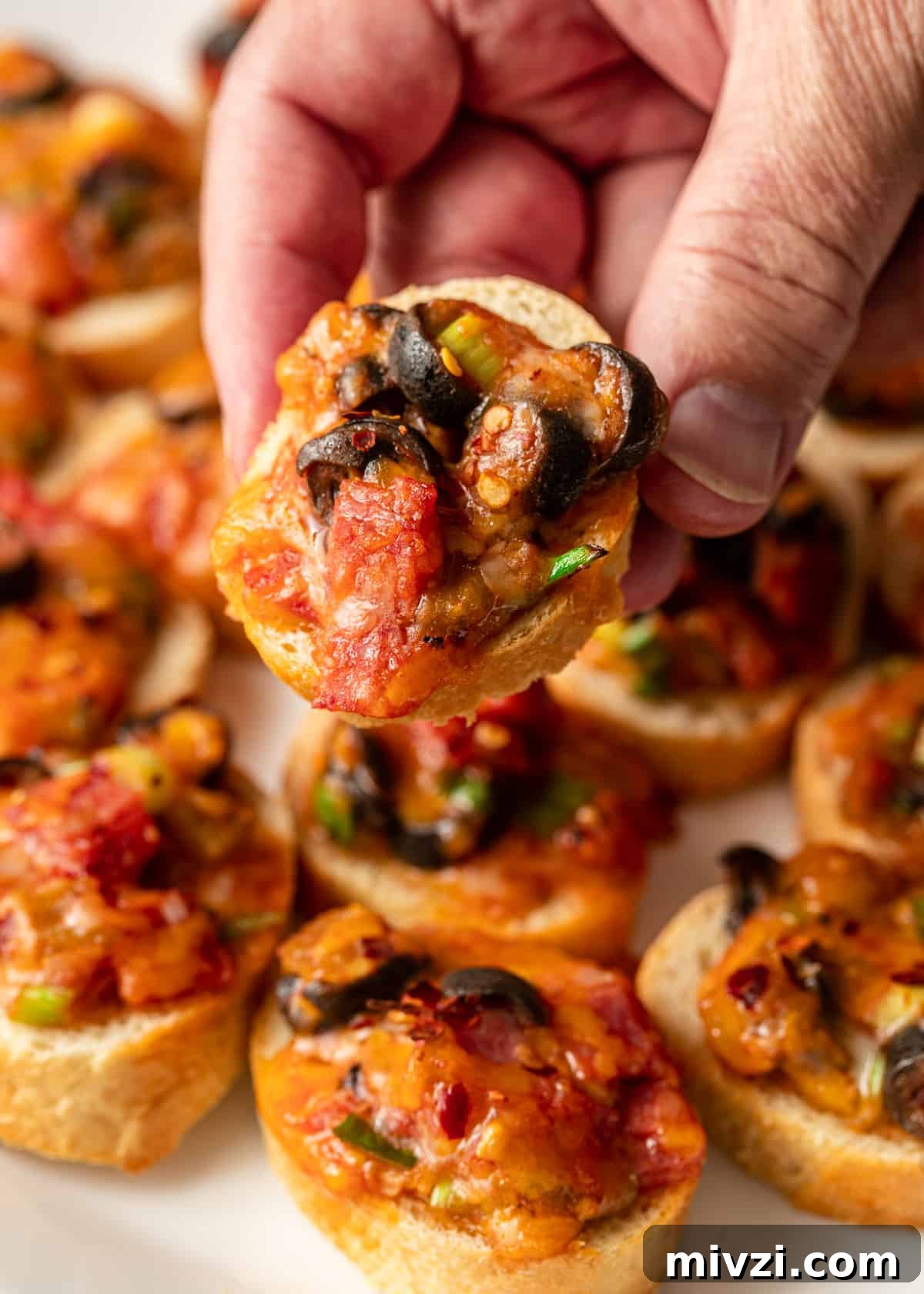 Mini Pizza Bites: Quick Party Appetizers for Any Occasion 8 hand holding mini pizza bite