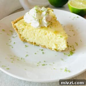 gluten free key lime pie on a plate next to limes topped with whipped cream and lime zest