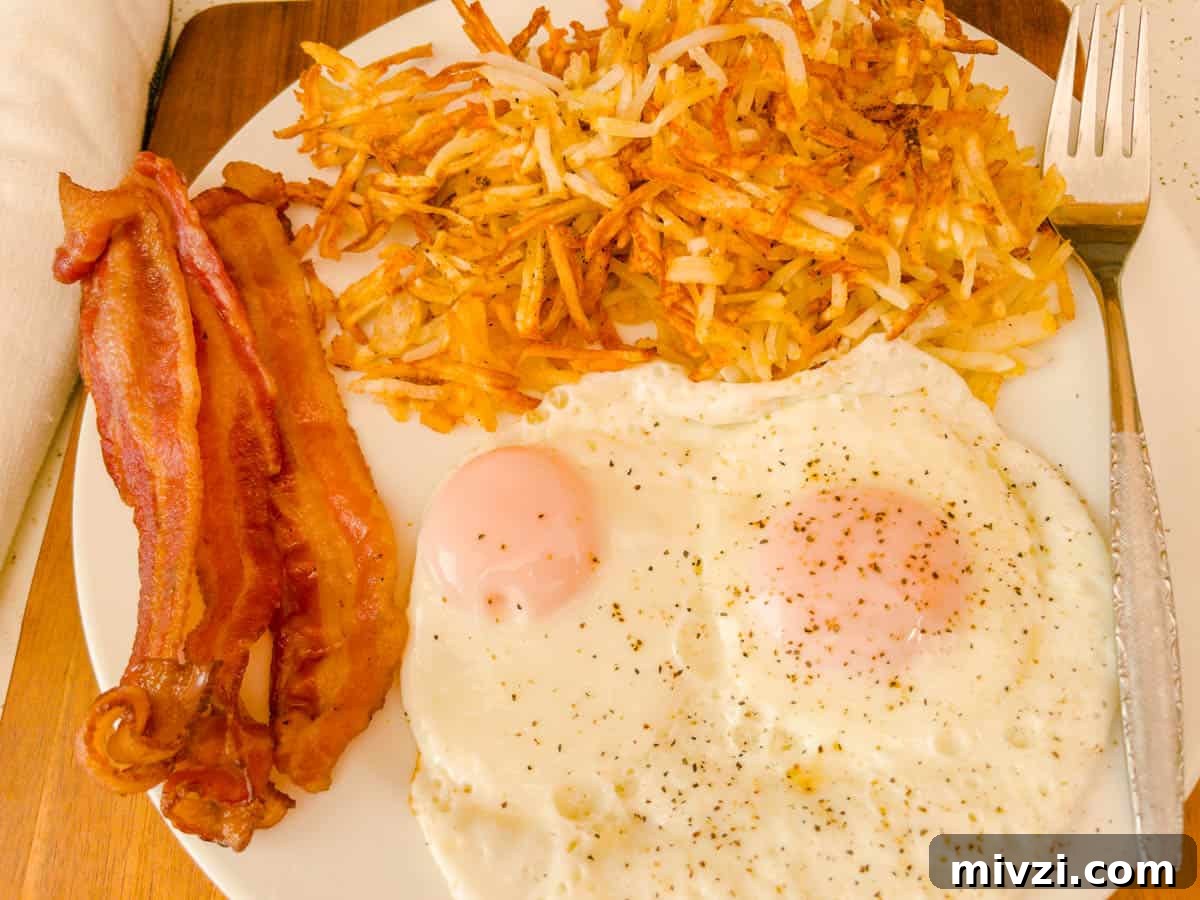 Crispy Air Fryer Hash Browns in 15 Minutes 2 Bacon over easy eggs on a plate with hash browns